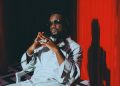 Sarkodie in a white outfit in front of a red curtain, shared with his announcement of the single Cold