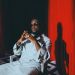 Sarkodie in a white outfit in front of a red curtain, shared with his announcement of the single Cold